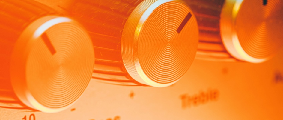 an extreme close-up of knobs used to adjust bass and treble, with an orange colour filter